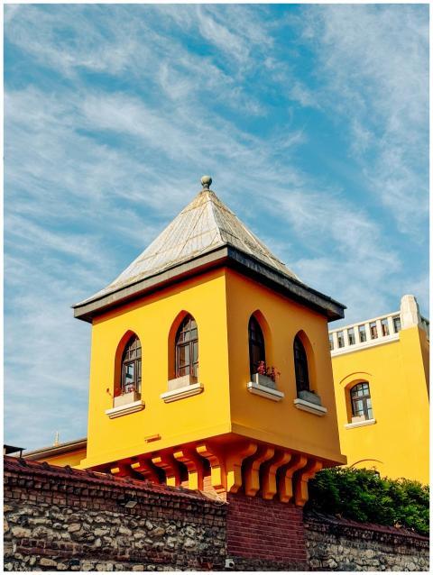 Bright yellow Ottoman-style tower under a vibrant