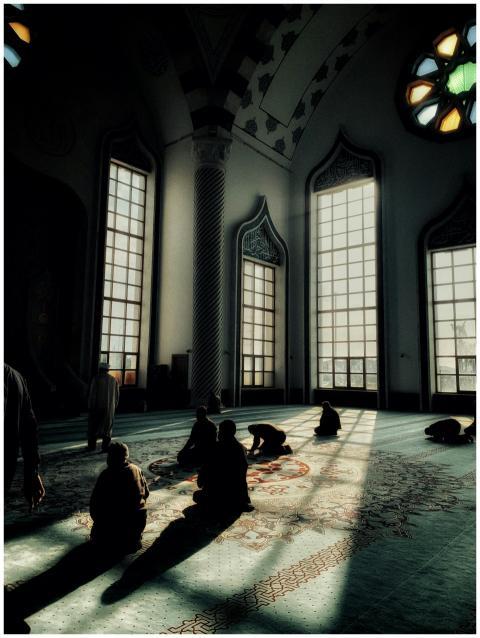 Silhouetted individuals praying inside a sunlit mo
