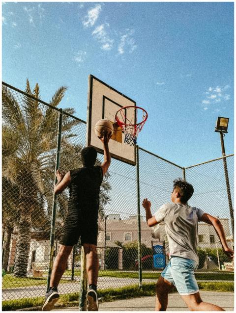 Two young men playing basketball together on an ou
