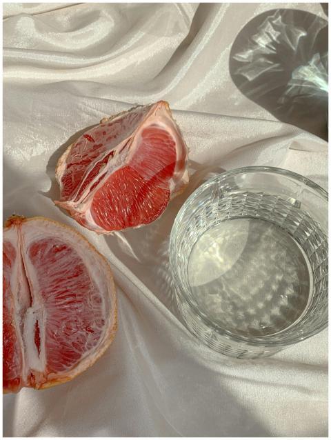 Close-up of sliced grapefruit and glass of water o