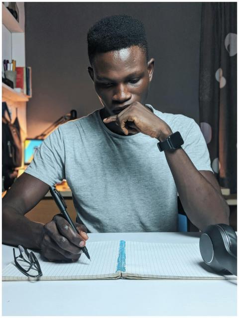 Man deeply focused while writing in a notebook on