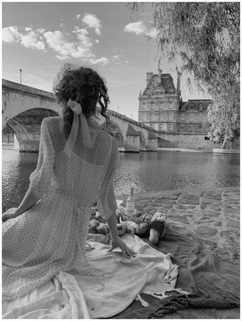Elegant woman enjoys riverside picnic with a citys