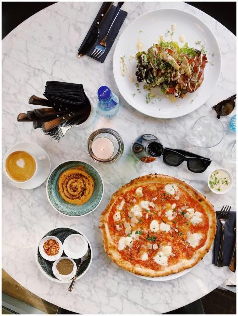 Aerial shot of a dining table with pizza, salad, c