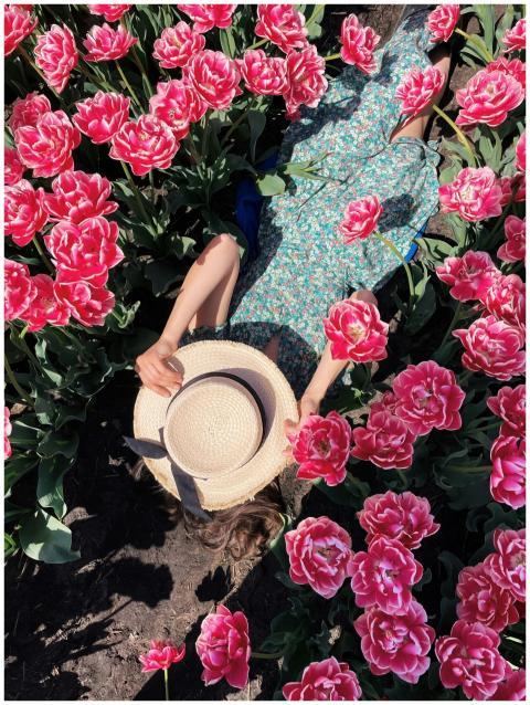 A woman in a floral dress and sunhat relaxes amids