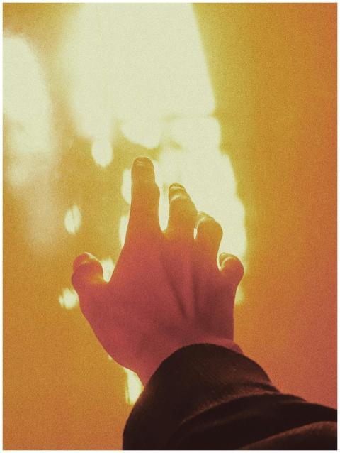 A silhouetted hand reaching towards warm glowing s