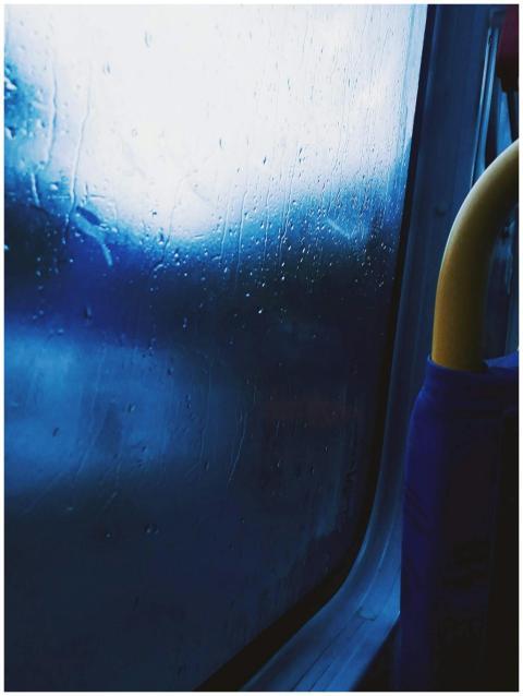 Raindrops on a bus window create a moody, abstract