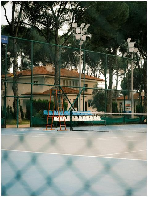 An empty outdoor tennis court surrounded by trees,