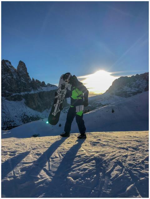 A snowboarder carrying a board on snowy mountain a