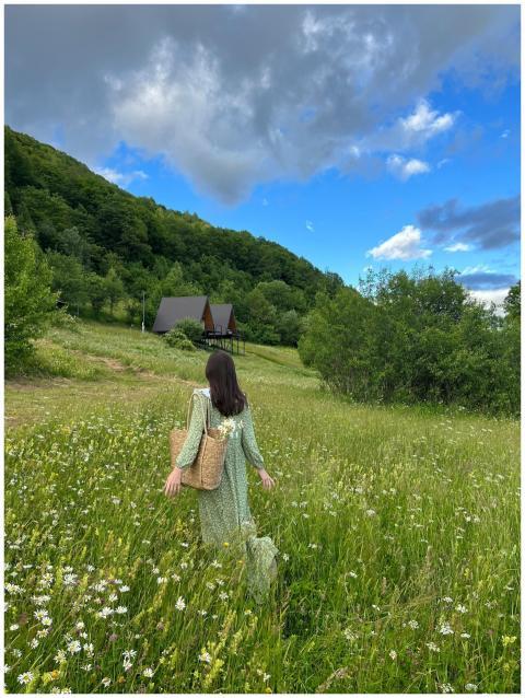 A woman in a green dress walks through a flower-fi