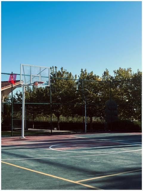 A serene basketball court outdoors with clear skie