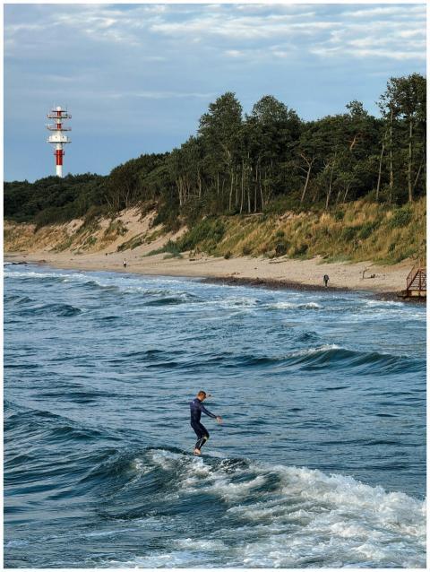 Surfer catching waves near a lighthouse on a sceni
