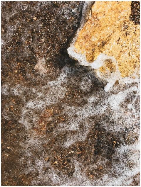 Detailed view of sea foam washing over a textured