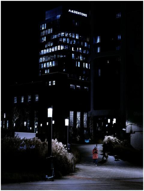 Illuminated skyscraper at night with a person walk
