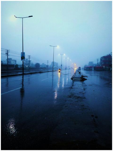 Rain-soaked street at twilight with glowing street