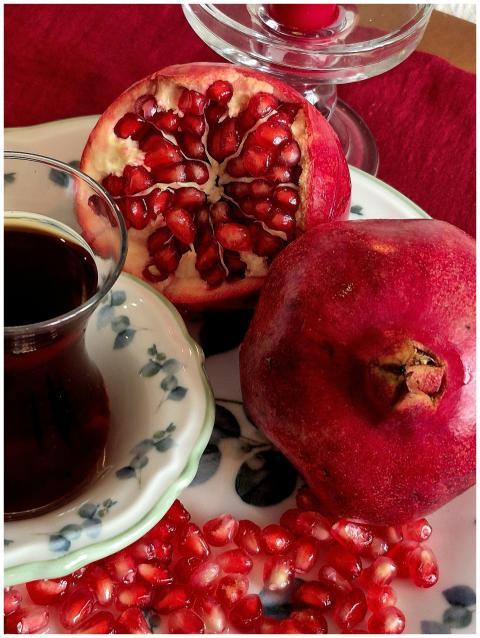 Fresh pomegranate with tea on a floral plate, rich