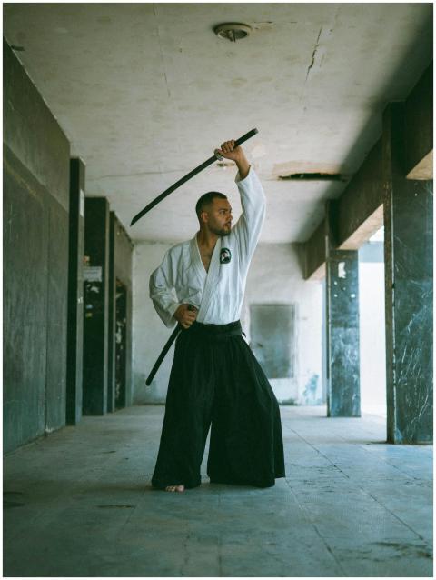 Martial artist practicing sword techniques in an u