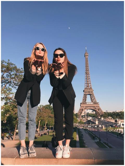 Two stylish women pose in front of the Eiffel Towe