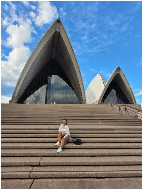 A woman is sitting on the steps of the iconic Sydn