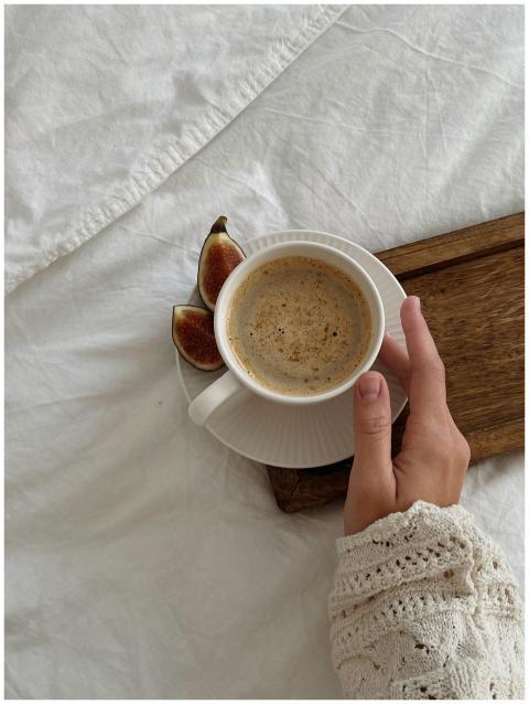 A close-up of a hand holding a coffee cup with fig