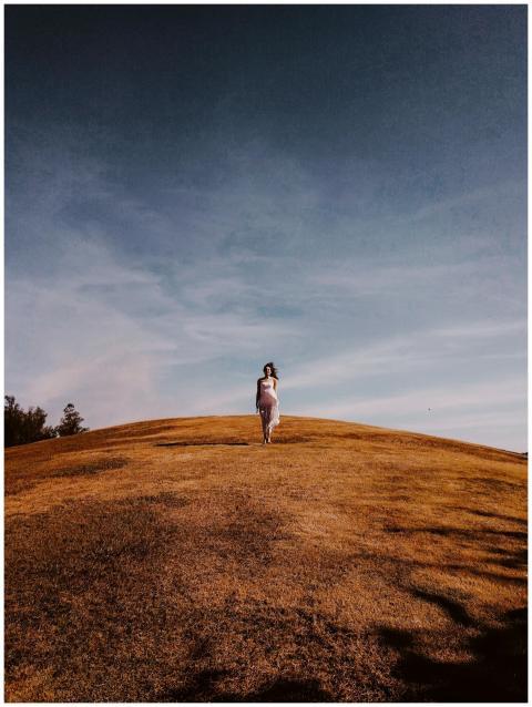 Solitary figure on a windswept grassy hill under a