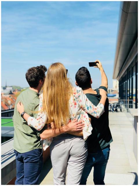 A group of adults taking a selfie on a sunny rooft