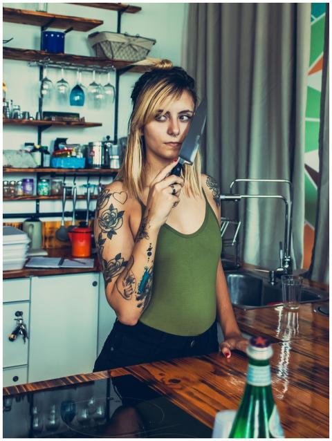 A woman stands in the kitchen with a knife, showca