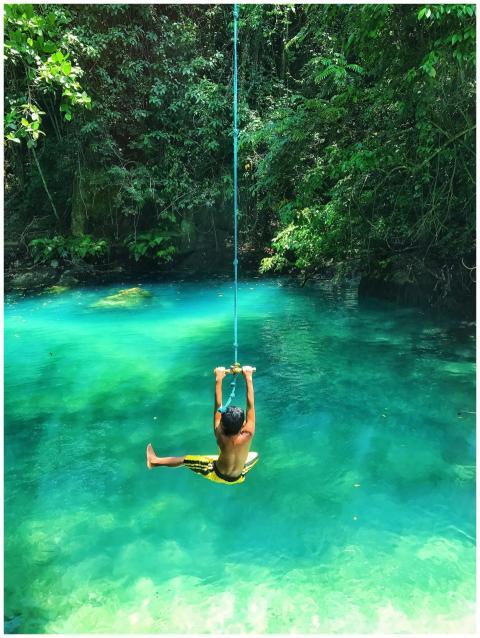 A child swinging joyfully on a rope over a stunnin