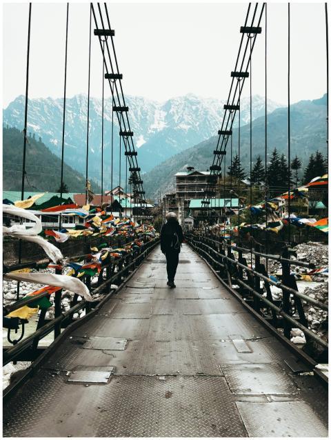 A lone traveler crosses a colorful bridge in Himac