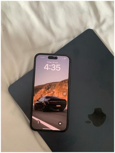 Smartphone displaying car wallpaper rests on a clo