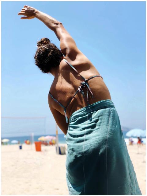 A woman stretching on a sunny day at Leblon Beach,
