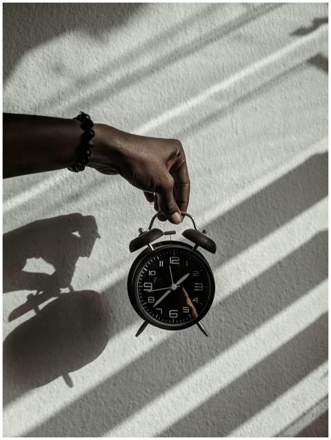 Close-up of a hand holding a vintage alarm clock c