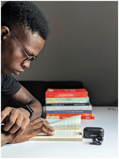 A man immersed in reading a book at a table surrou