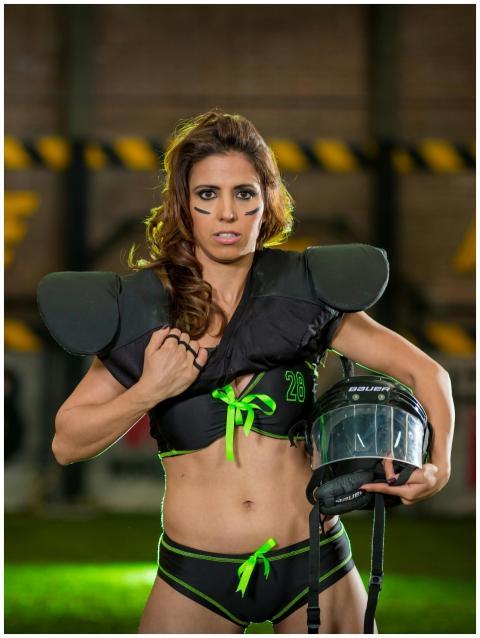 Athletic woman in football gear poses confidently