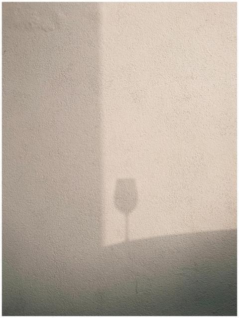 Subtle shadow of a wineglass cast on a textured wa