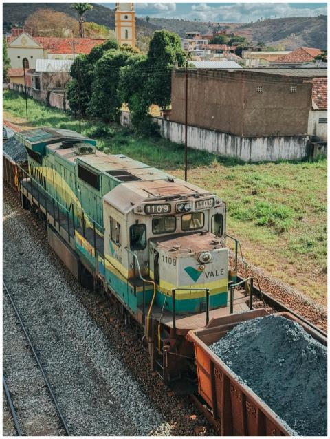 A vibrant freight train travels through a scenic r