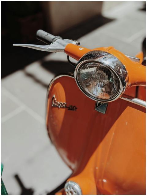 Close-up of a vintage orange Vespa scooter parked