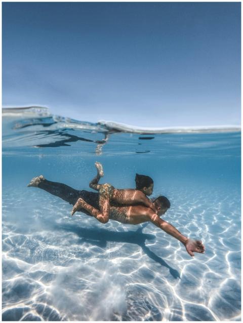 A father and daughter swimming underwater in a cle