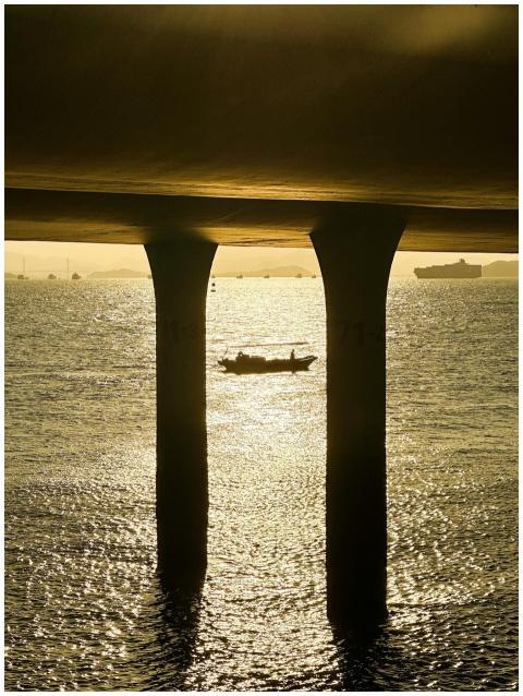 A peaceful scene of a boat silhouetted under a bri