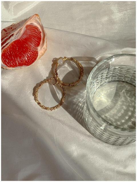 Close-up of grapefruit, gold earrings, and glass o