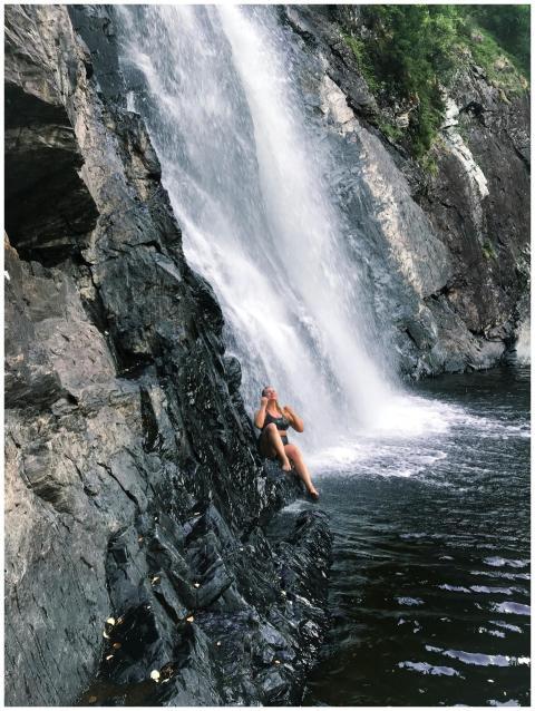 A woman sitting by a stunning waterfall in Norway,