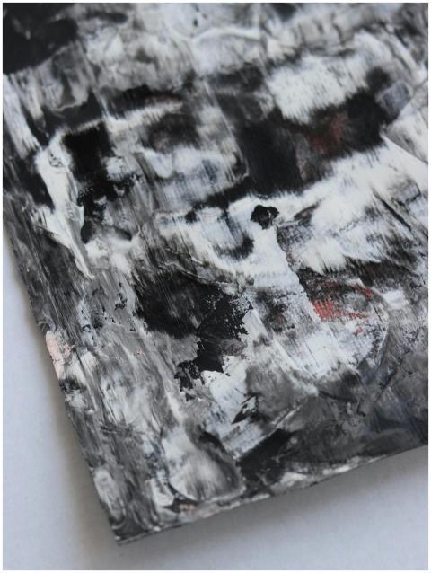 A close-up of a textured abstract painting in blac