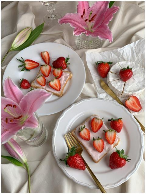 Sliced strawberries on frosted pastries surrounded