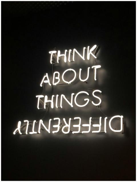 A glowing neon sign displaying an upside-down moti