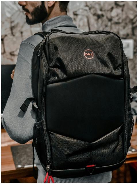 Close-up of a man wearing a Dell backpack indoors
