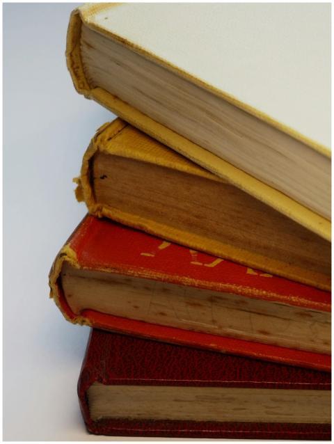 A stack of vintage hardcover books showcasing worn