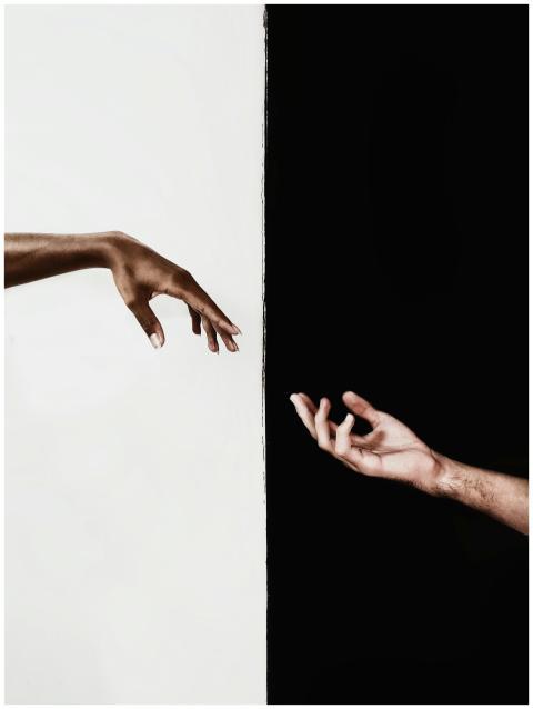 Two hands reaching across a stark black and white