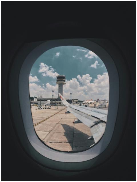 Airplane wing view through window showing airport