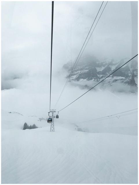 Cable cars ascending snowy mountains through misty