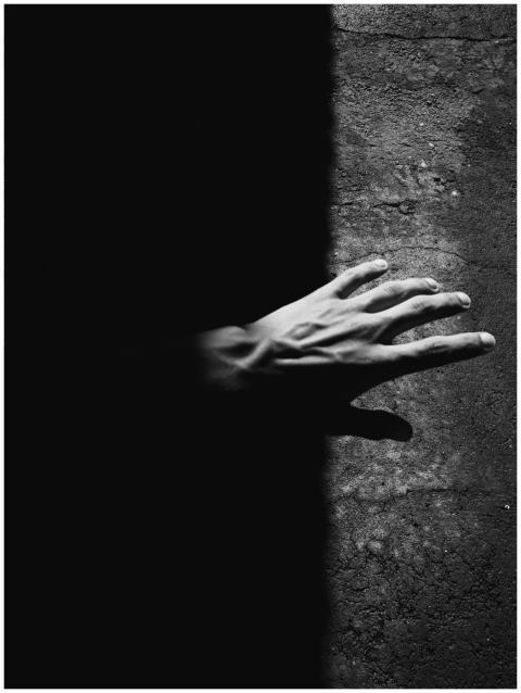Monochrome image of a hand reaching from darkness