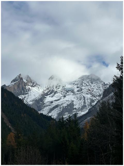 Snow-capped peaks of a mountain range under a clou